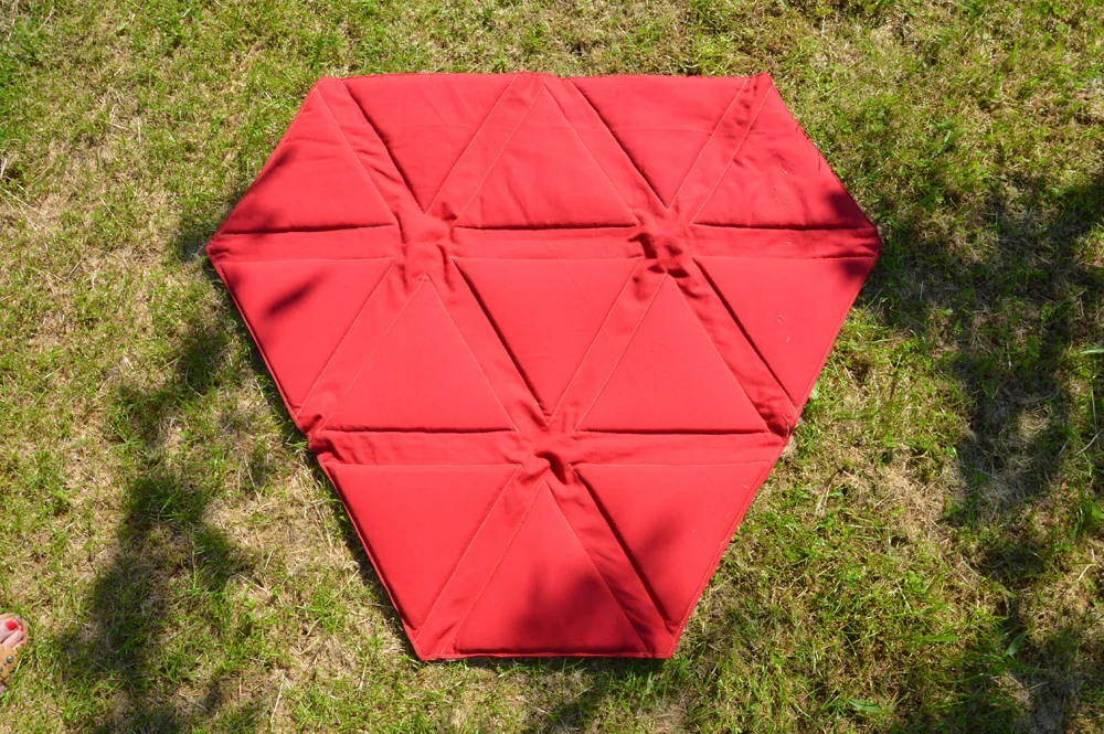 Surface textile rouge dépliée sur une pelouse