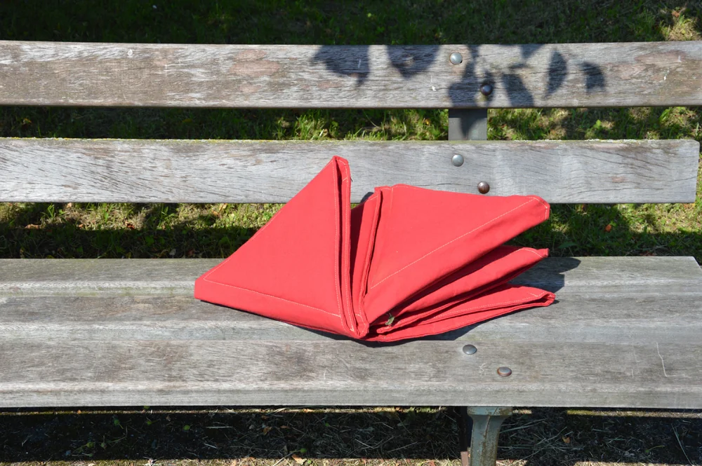 Surface textile rouge pliée sur un banc public