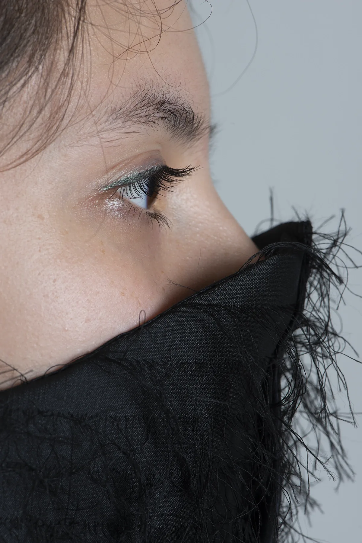 Profil, col noir effrangé couvrant le bas du visage