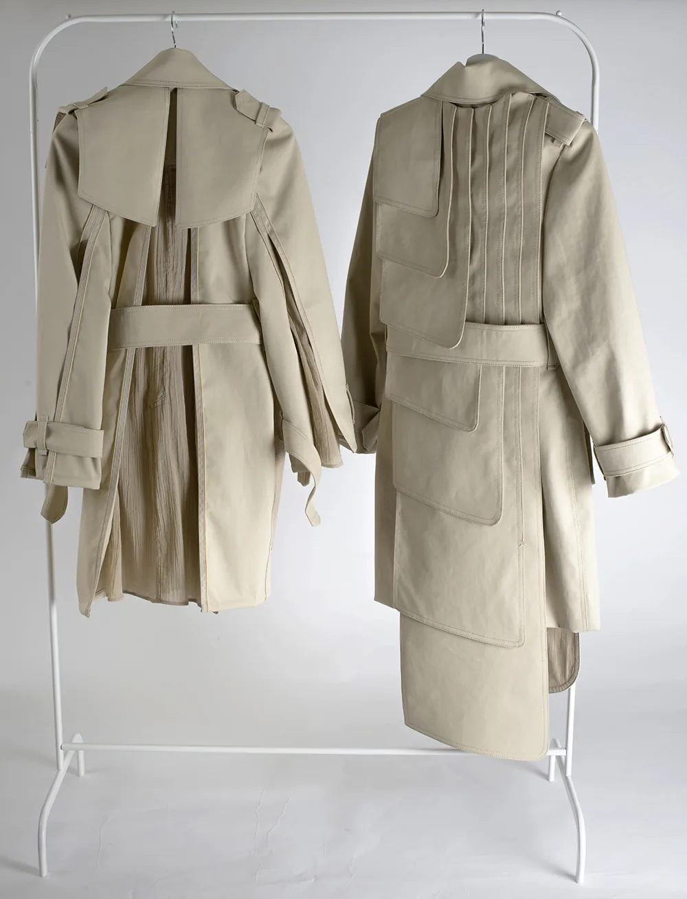 Deux trench-coats beiges retravaillés sur un portant