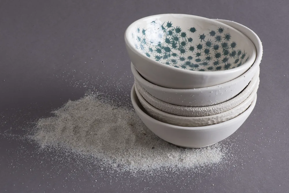 Pile de bols en porcelaine aux fonds mouchetés de bleu, sable
