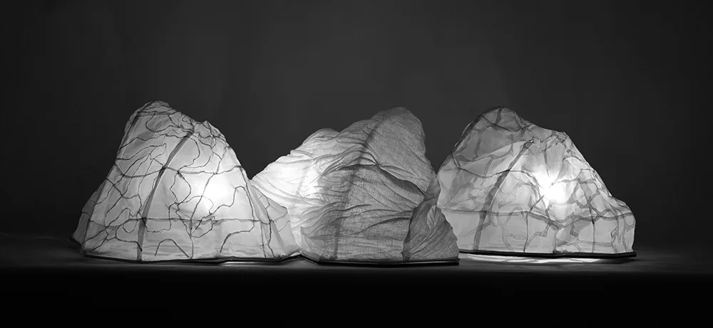 Trois reliefs textiles blancs éclairés de l’intérieur sur fond noir