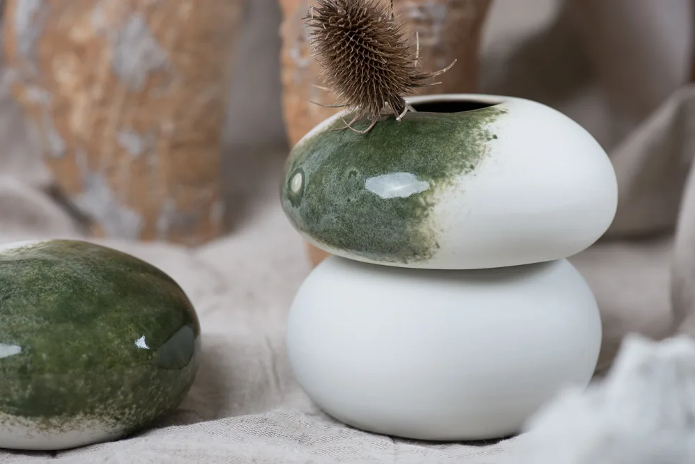 Galets en porcelaine blanche émaillés de vert, empilés, avec un chardon