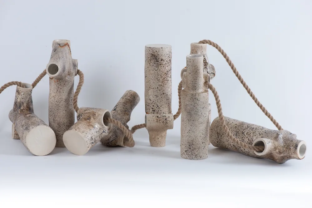 Ensemble de pièces cylindriques en grès moucheté reliées par des cordes