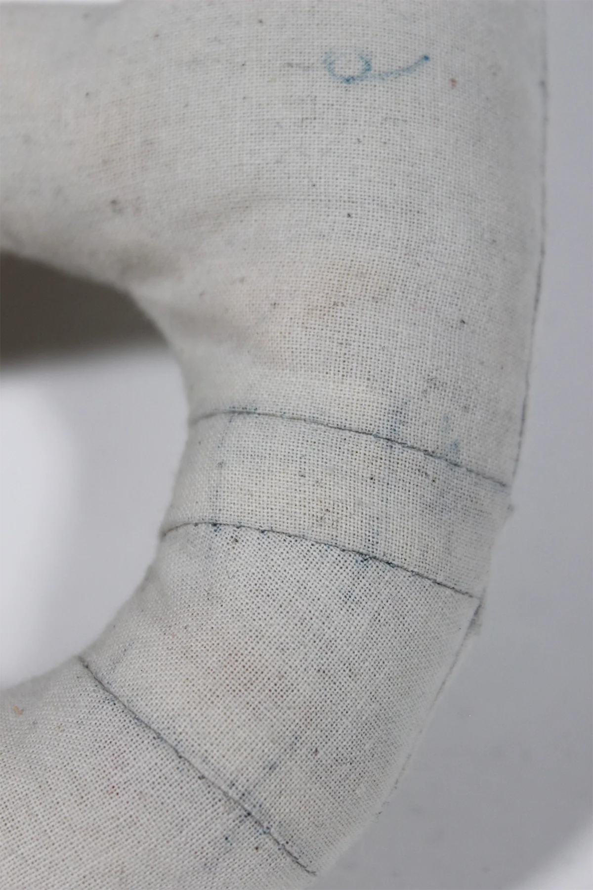 Détail d’un moulage textile écru rembourré, coutures apparentes
