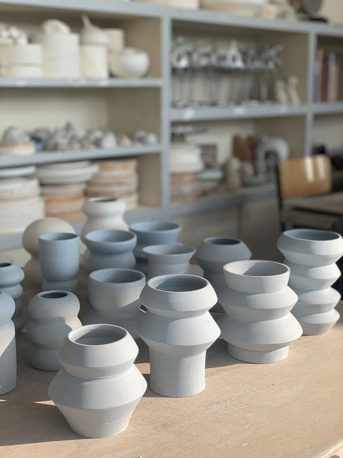 Série de vases tournés gris-bleu sur une table d’atelier