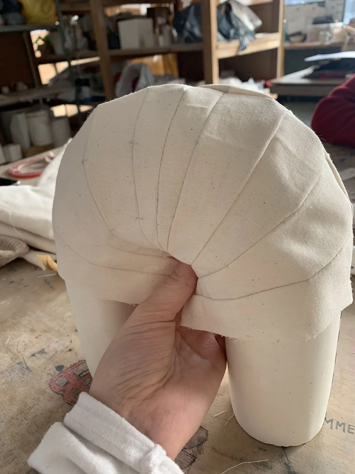 Forme en arche modelée dans un textile écru, tenue à la main