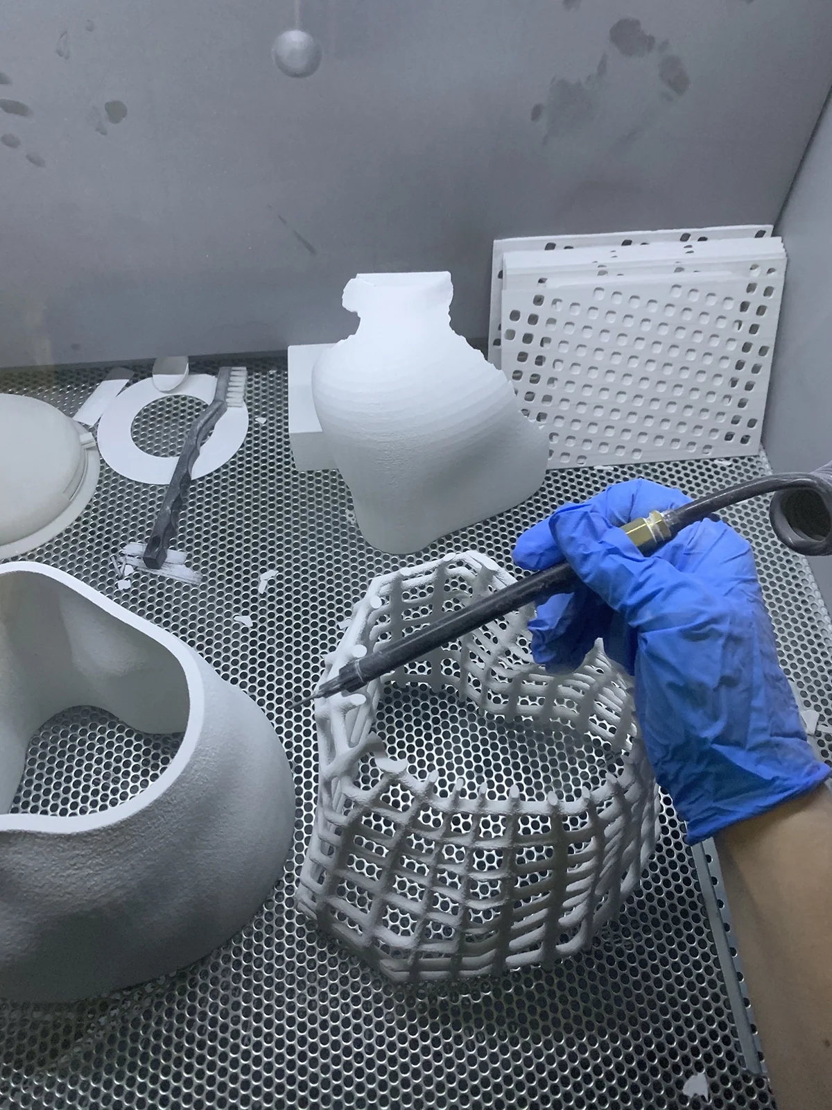 Dépoussiérage d’une pièce imprimée en 3D en résille, dans la cabine d’impression