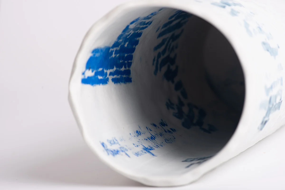 Intérieur d’un tube de porcelaine couché, couvert d’écritures bleues