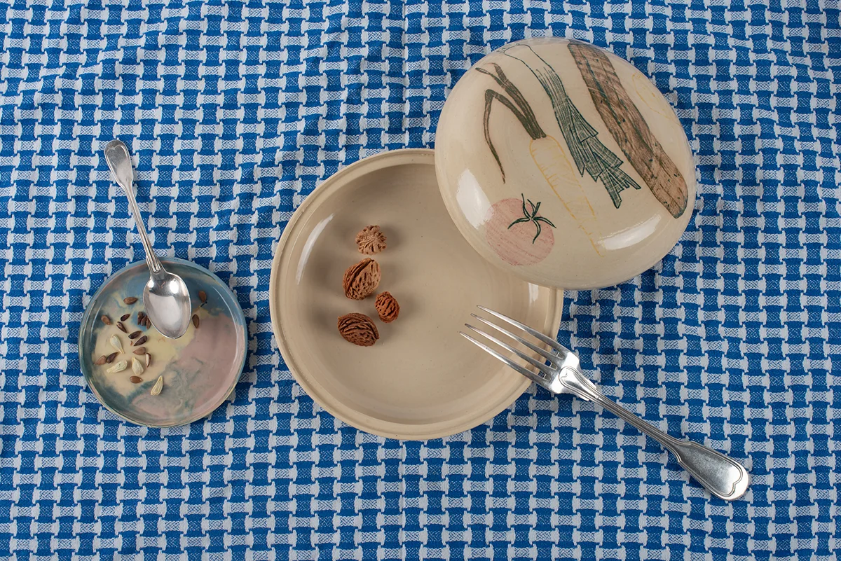 Mise en scène d’un repas : assiette, coupelle et cloche sur nappe bleue