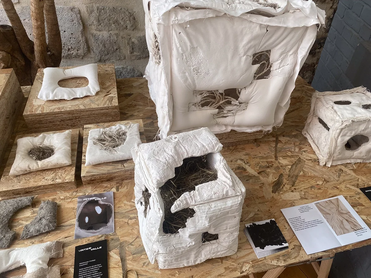 Vue d’exposition : prototypes textiles et échantillons sur une table en bois