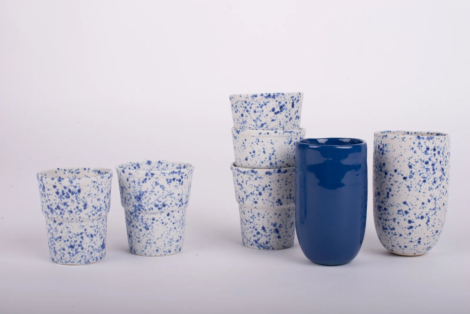 Série de gobelets en porcelaine coulée, mouchetés de bleu, et gobelet bleu uni