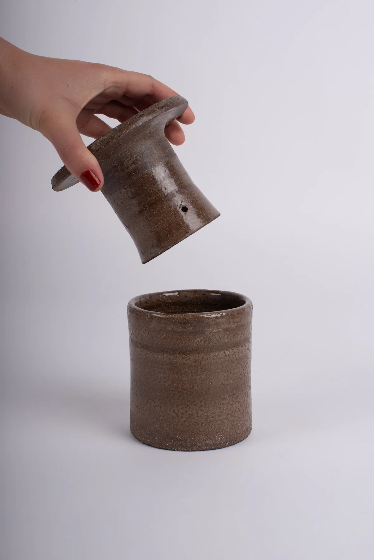 Beurrier à eau en grès tourné : une main soulève la cloche